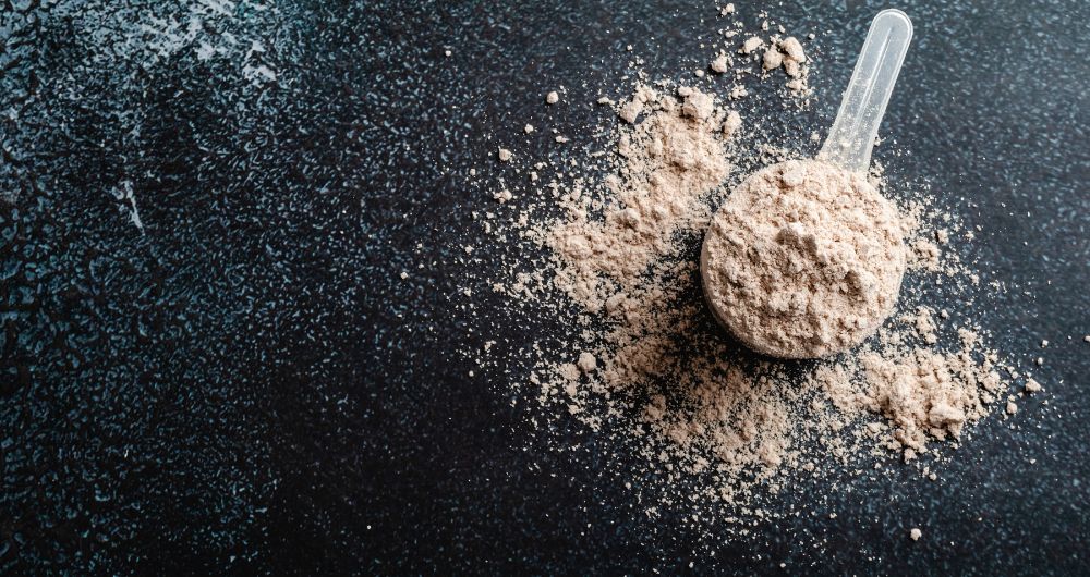 Scoop of protein powder on a dark surface