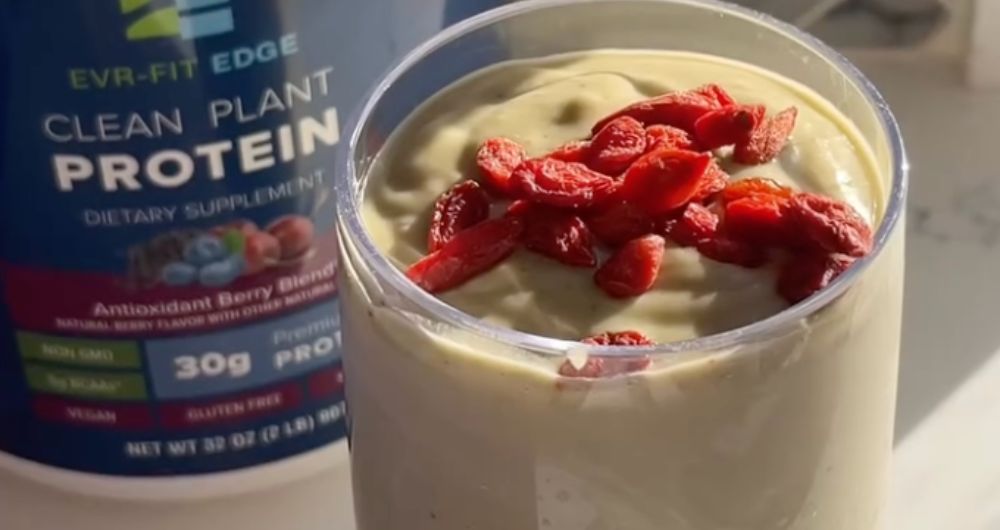 Protein smoothie topped with berries beside EVRFit Edge Clean Plant Protein supplement container.