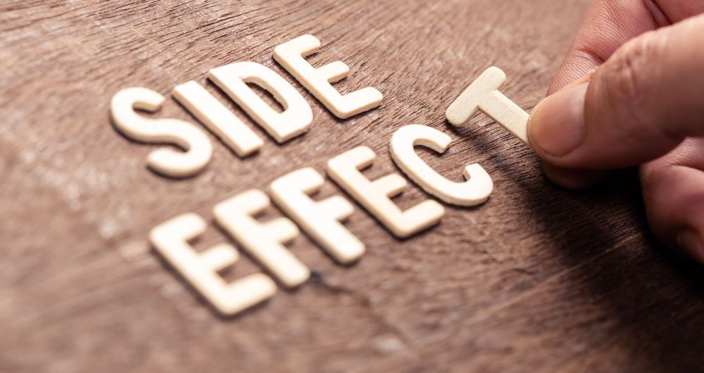 Hand placing the letter “T” to complete the phrase “Side Effect” on a wooden surface